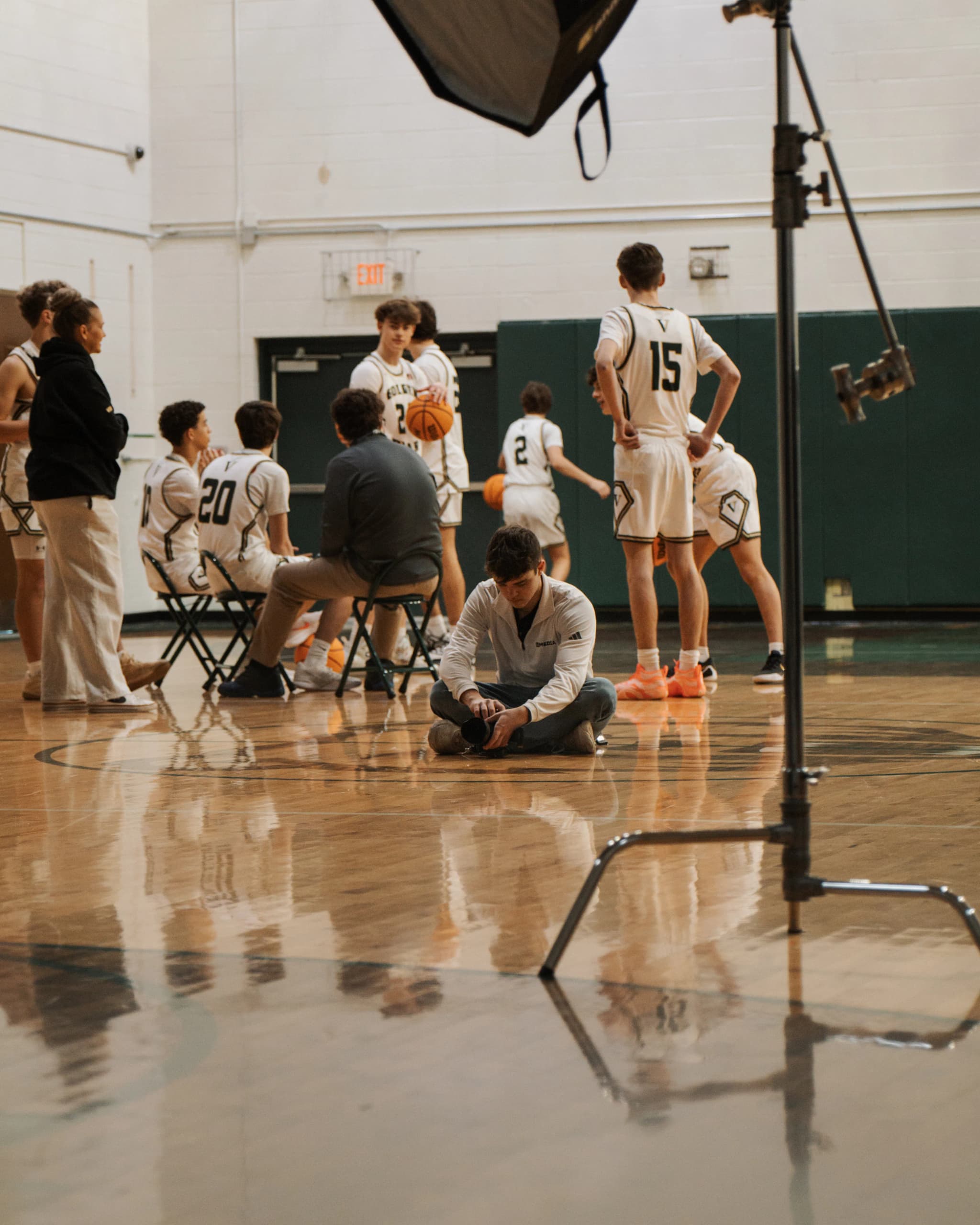 Cole at center court adjusting his camera during a basketball media day