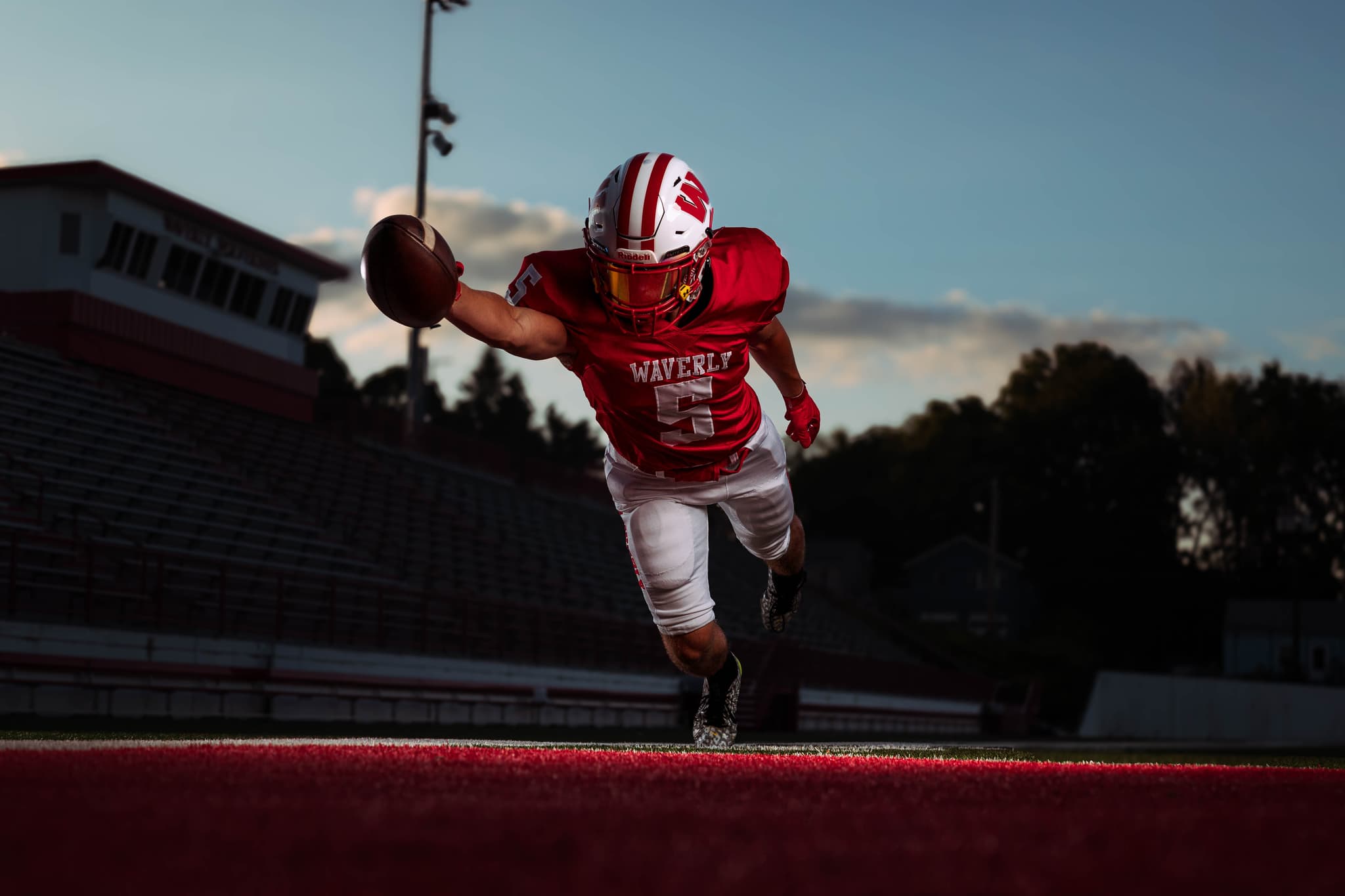 A Waverly football player diving into the end zone with the ball outstretched at dusk